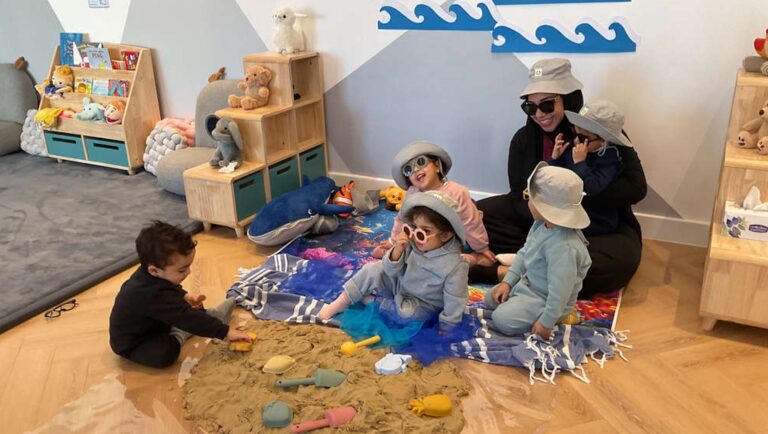 Children exploring phenomenon beach and water with the teacher