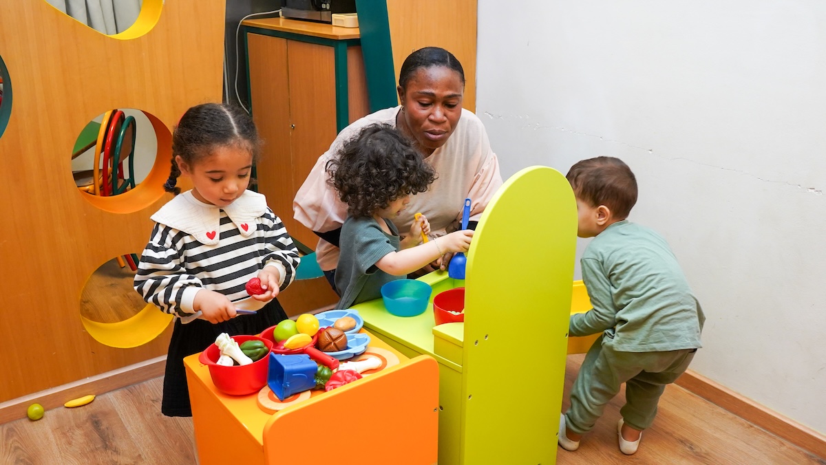 Nursery school teacher guiding children during play-based learning